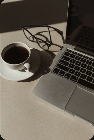Mesa de trabalho com café, óculos e computador